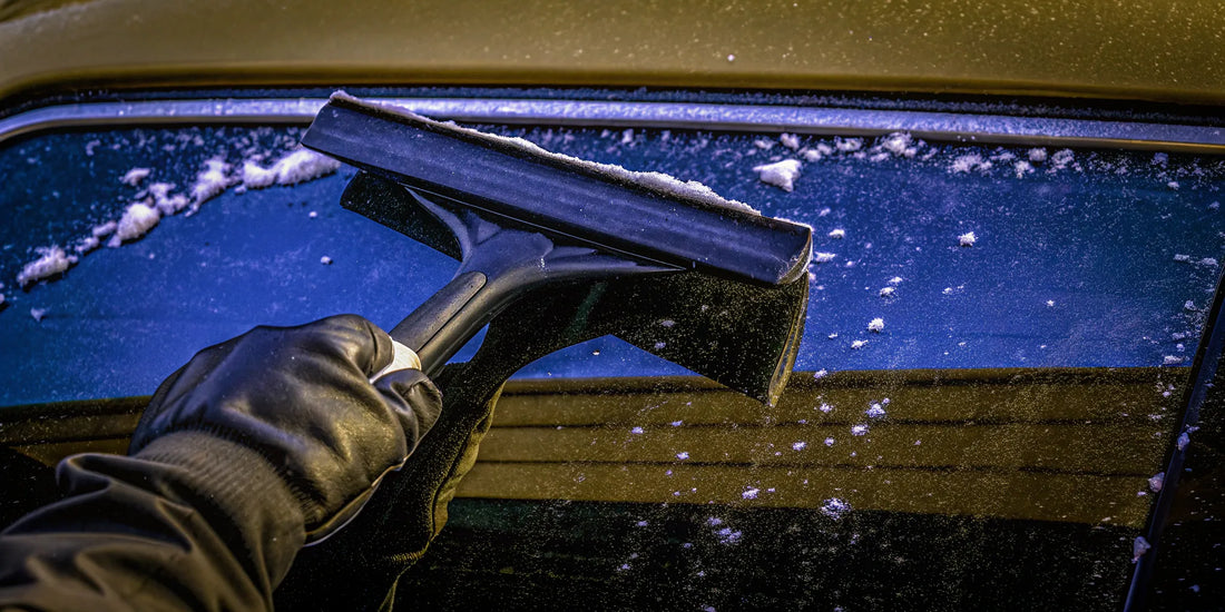 A durable snow scraper clearing thick snow and ice from a car windshield.