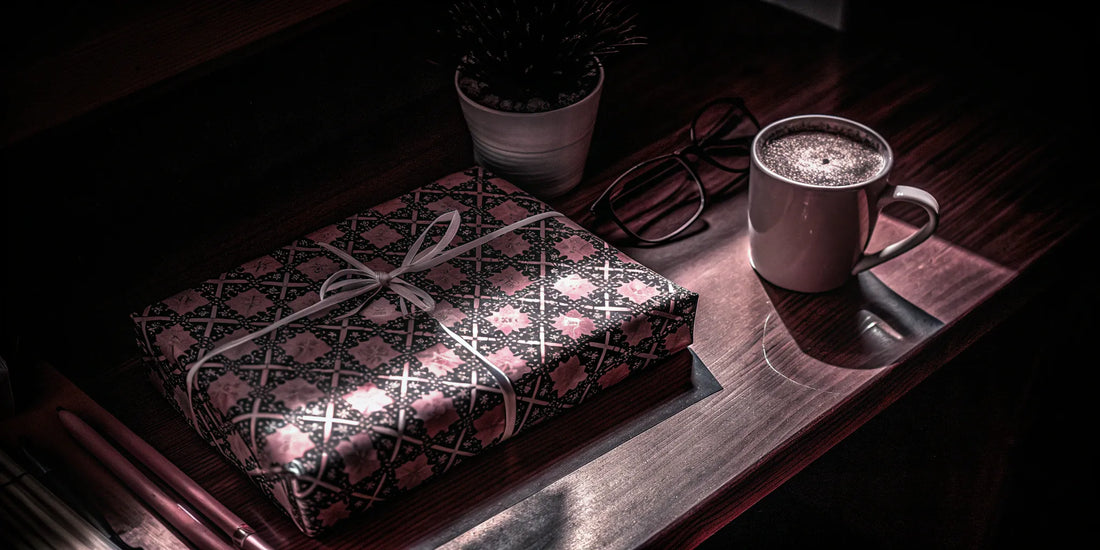 A wrapped gift, coffee mug, and glasses on a desk, a thoughtful company holiday gift for employees.