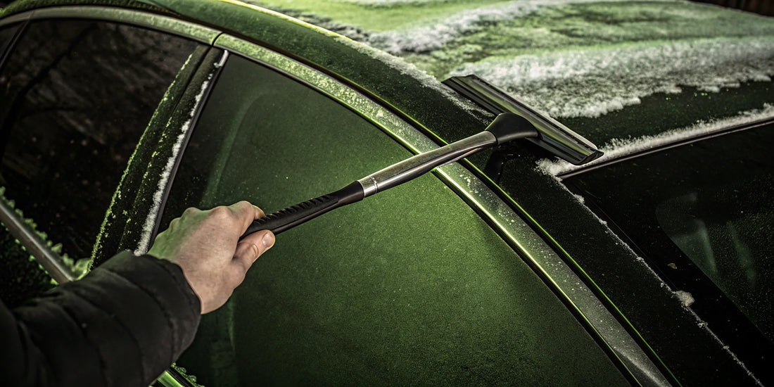 A long handle ice scraper easily reaching across a car windshield to remove ice.