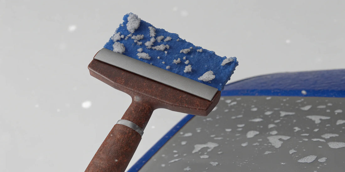 A durable ice scraper breaking through thick ice on a frozen car windshield.