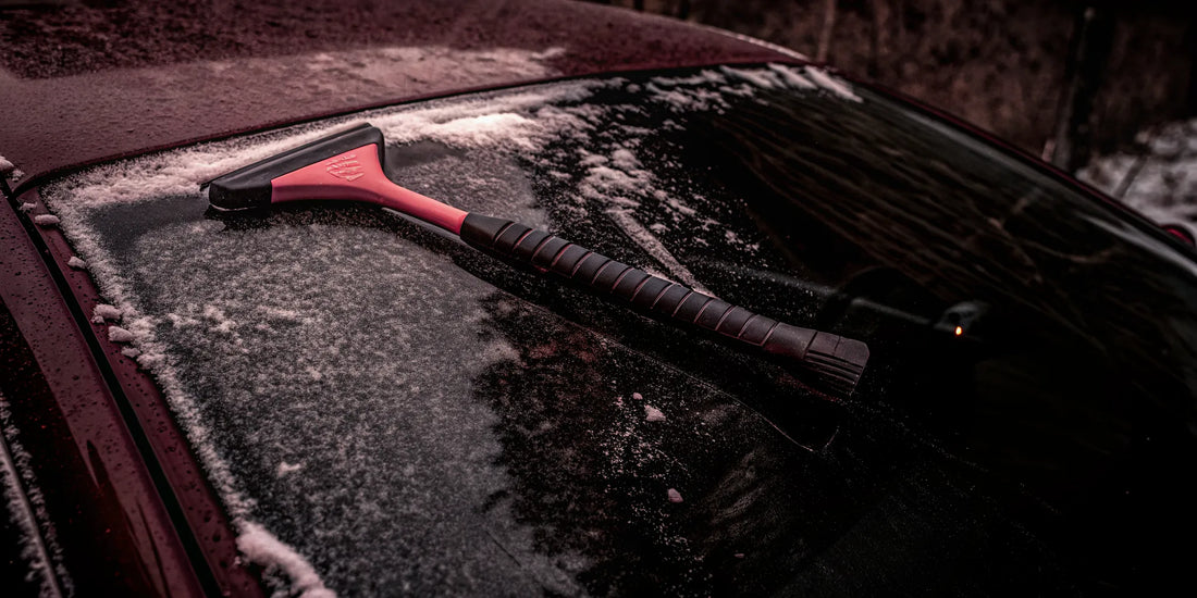 The Edge snow and ice scraper resting on a frosty car windshield showing its ergonomic grip and paint-friendly edge