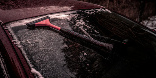 The Edge snow and ice scraper resting on a frosty car windshield showing its ergonomic grip and paint-friendly edge