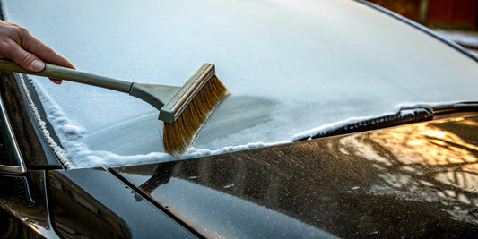 A plastic snow scraper clearing a car windshield, a tool that is unsafe for car paint.