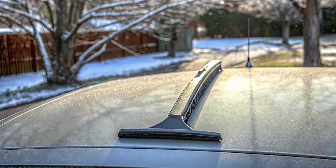 A durable ice scraper clearing thick ice from a car's frosty windshield.