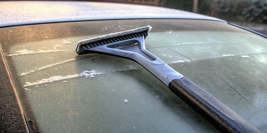 An ice scraper clearing thick ice from a car's windshield.
