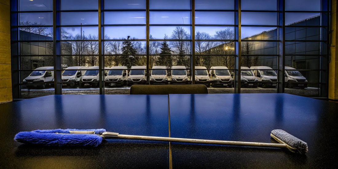 A row of fleet snow scrapers ready to buy online, with commercial service vans in the background.