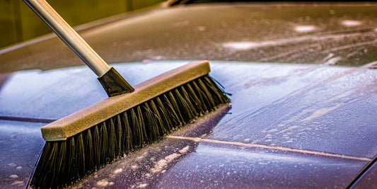 A snow brush's stiff bristles scratching a car's paint.