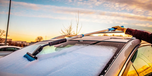 A long snow scraper for an SUV clearing thick snow from the windshield.