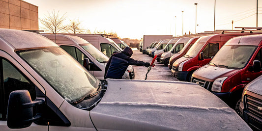 Driver clearing a fleet vehicle windshield before a winter shift