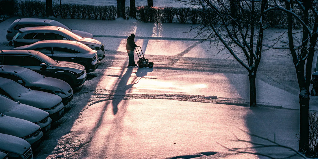 A person using a long-handled snow broom to quickly clear snow off multiple cars.
