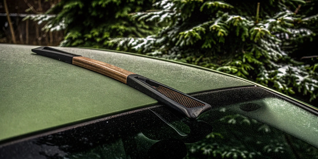 Using a scraper to safely remove stubborn ice from a frozen car wiper blade.