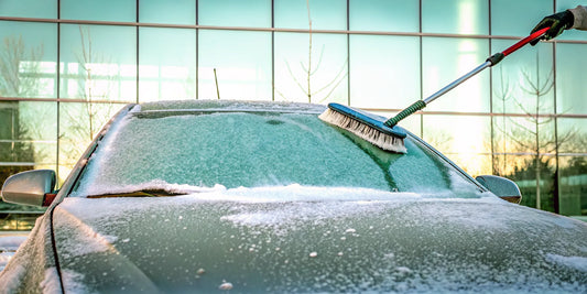 Removing snow from a car with a soft brush without scratching the paint.