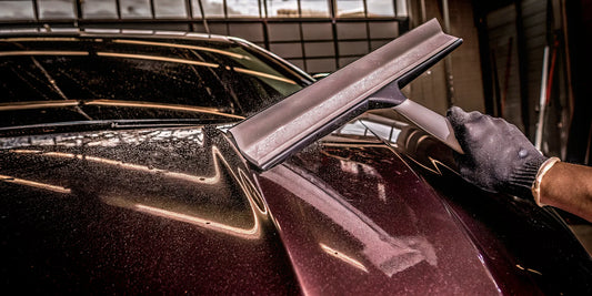 A paint-safe ice scraper clearing ice from a car hood, protecting the paint from scratches.