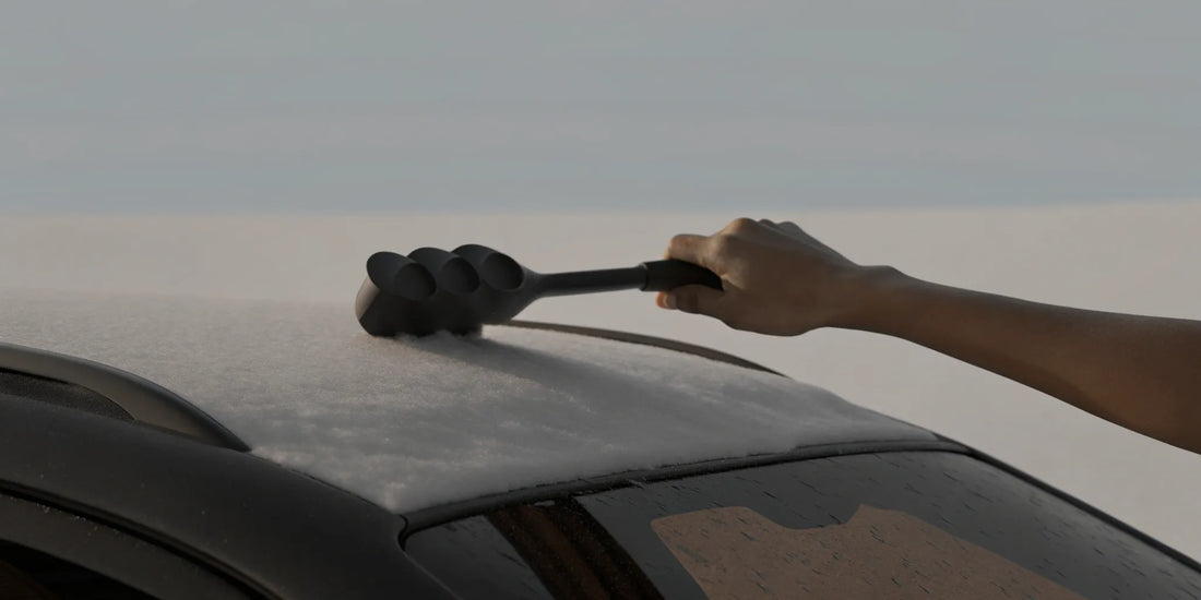 A person using one of the best ice scrapers to clear thick frost from a car windshield.