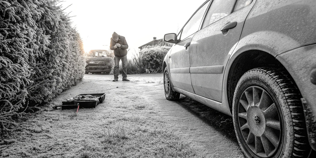 A man follows a winter car maintenance checklist while checking his car's engine on a frosty morning.