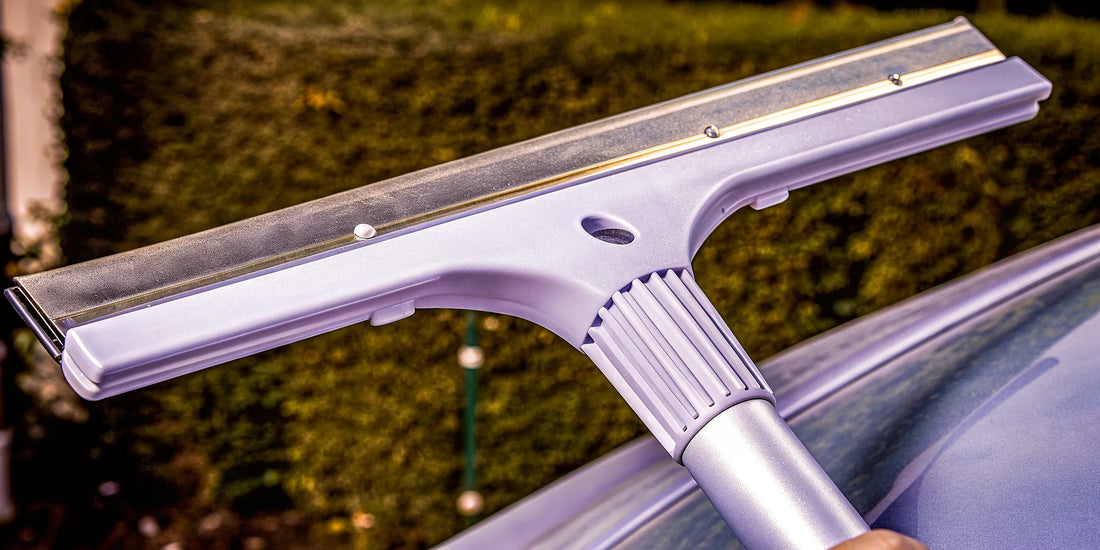 A durable ice scraper with a wide blade and strong grip clearing ice from a car windshield.