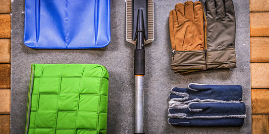 A winter driving essentials kit with a snow shovel, ice scraper, and warm gloves for a roadside emergency.