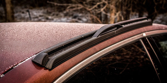 A heavy duty ice scraper breaking through thick ice on a frosted car roof.