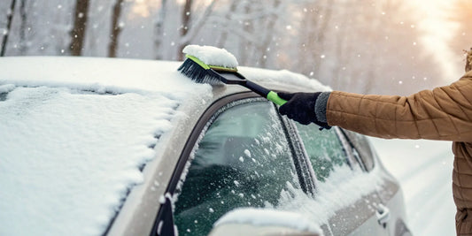 A person clearing snow from their car, an essential task for winter car care and driving safety.