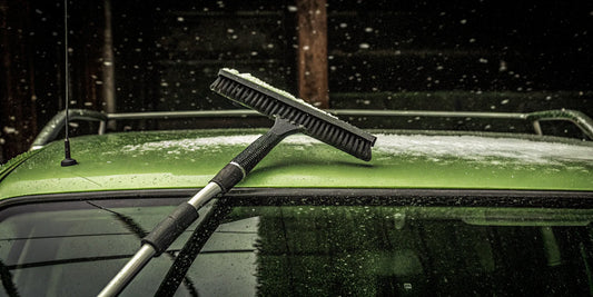Extra long snow remover clearing snow from a fleet vehicle roof.