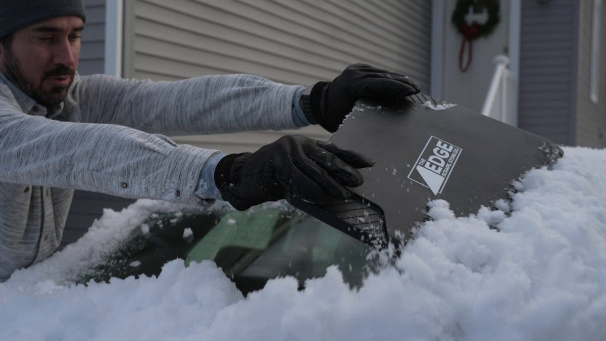 Two gloved hands clearing ice from a windshield with The EDGE