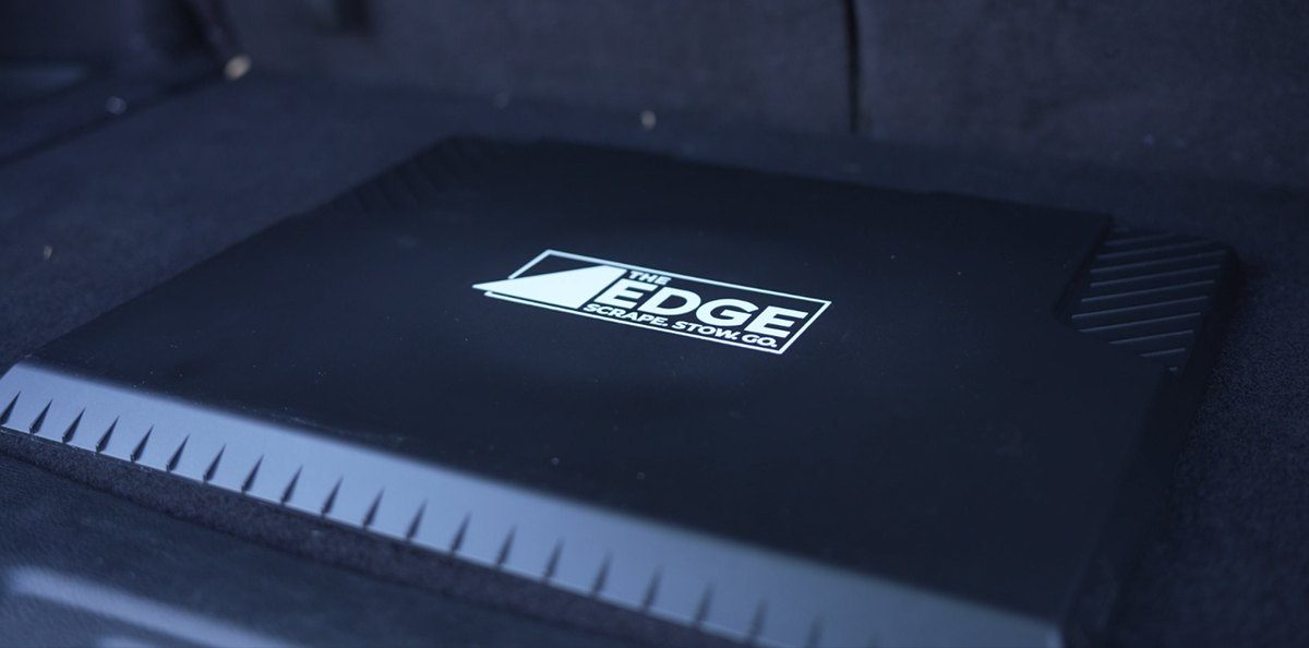 The EDGE lying flat, logo up, on a car trunk floor