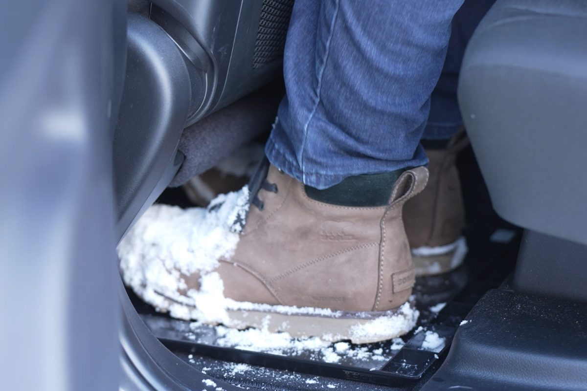 Snowy boots resting in The EDGE, turned logo side down on a car floor so it works as a tray