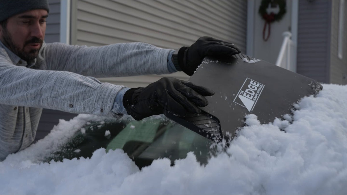 Gloved hands clearing a frosted windshield with The EDGE